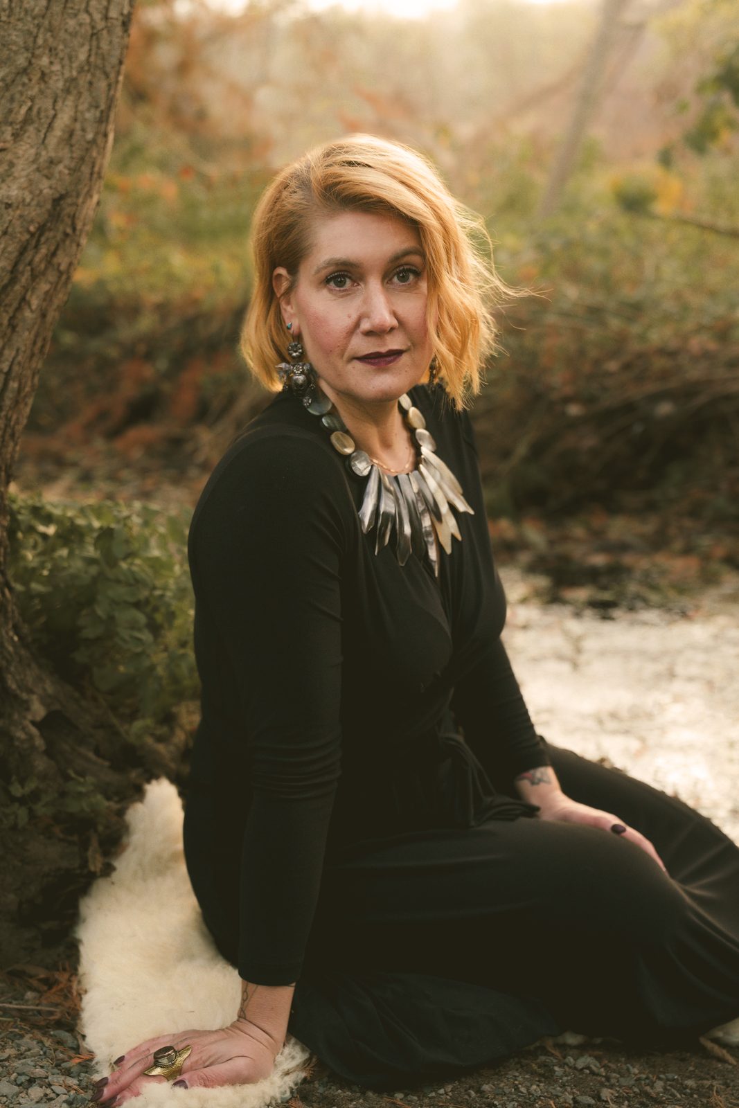 Portrait of Lara Woolfson seated by a tree at golden hour