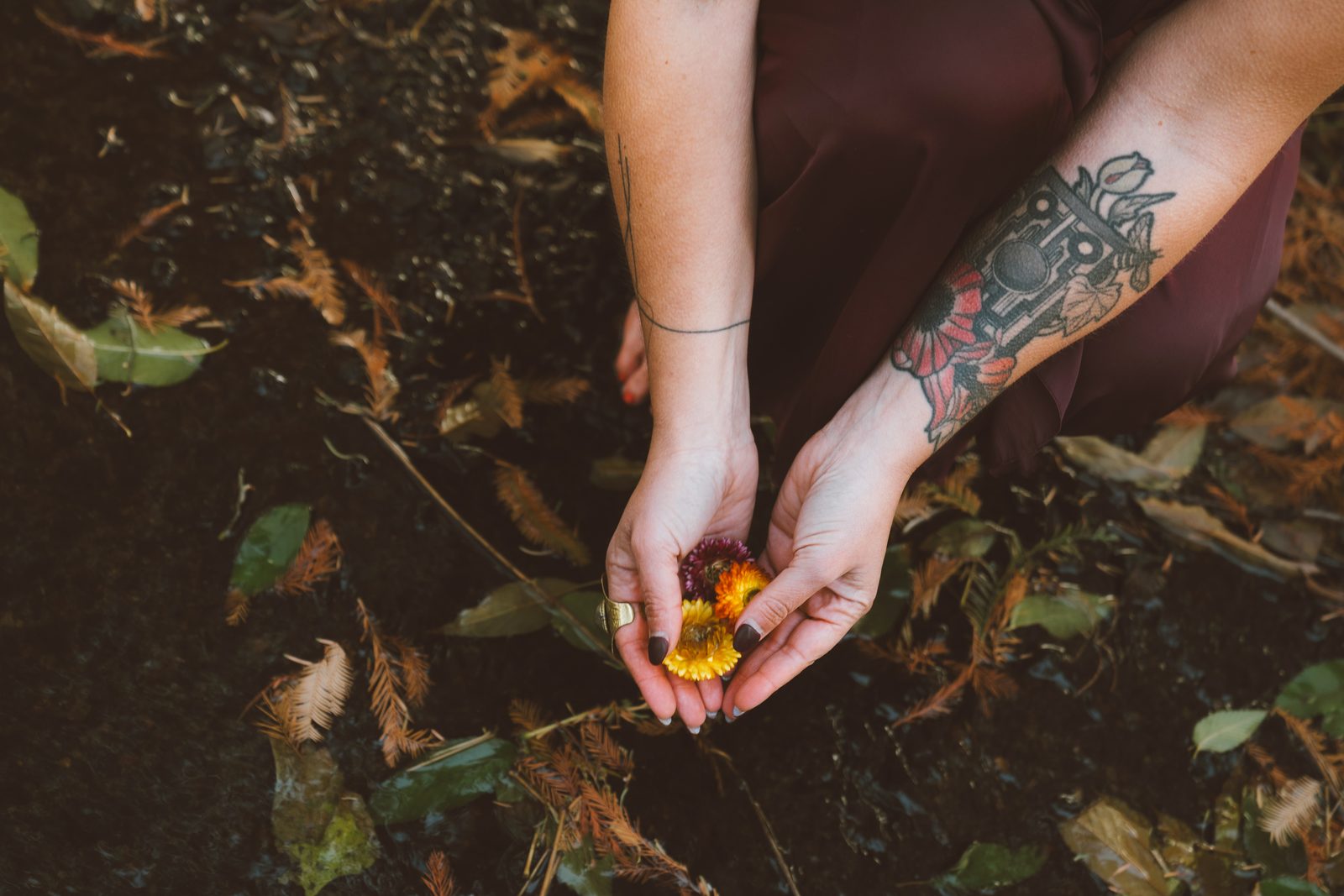Cupped hands holding wildflowers over the earth